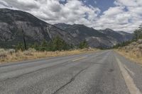 a empty empty road in front of mountains and a blue sky with white clouds above