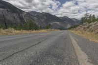 a empty empty road in front of mountains and a blue sky with white clouds above