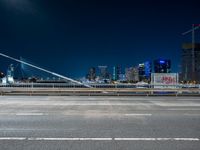 a picture of an empty road, which is next to a building at night with city lights