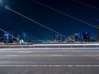 a picture of an empty road, which is next to a building at night with city lights