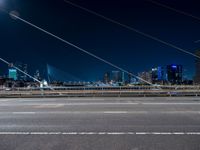 a picture of an empty road, which is next to a building at night with city lights