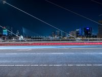 a picture of an empty road, which is next to a building at night with city lights