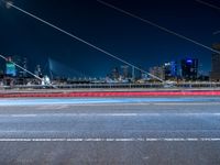 a picture of an empty road, which is next to a building at night with city lights