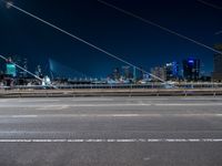 a picture of an empty road, which is next to a building at night with city lights