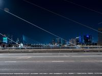 a picture of an empty road, which is next to a building at night with city lights