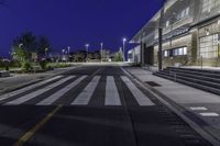 a empty road with several empty curbs and lots of buildings around it at night