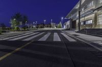 a empty road with several empty curbs and lots of buildings around it at night