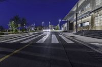 a empty road with several empty curbs and lots of buildings around it at night