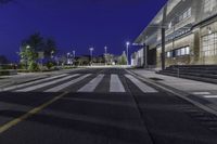 a empty road with several empty curbs and lots of buildings around it at night