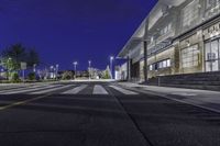 a empty road with several empty curbs and lots of buildings around it at night