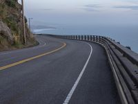 an empty road next to the ocean with a view of mountains in the background in hawaii