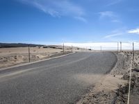 a paved beach with a fence in front of it and the ocean in the distance