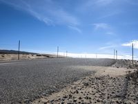 a paved beach with a fence in front of it and the ocean in the distance