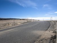 a paved beach with a fence in front of it and the ocean in the distance