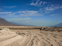 a sign on a post marks an empty road near a desert landscape with a mountain and cloud covered sky