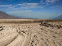 a sign on a post marks an empty road near a desert landscape with a mountain and cloud covered sky