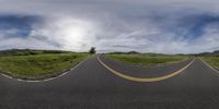 an empty road leads to a beautiful green valley with trees and a mountain in the distance