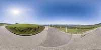 a 360 - view photo of an empty road in the hills on a bright sunny day