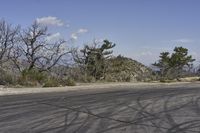 a view along a dirt road of an empty field and mountains in the distance of the scene