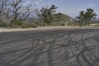 a view along a dirt road of an empty field and mountains in the distance of the scene