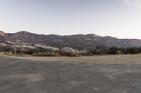 an empty road in the middle of the mountains with a stop sign in the distance