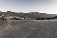 an empty road in the middle of the mountains with a stop sign in the distance