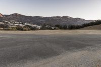 an empty road in the middle of the mountains with a stop sign in the distance