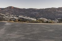 an empty road in the middle of the mountains with a stop sign in the distance