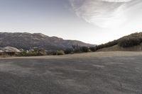 an empty road in the middle of the mountains with a stop sign in the distance