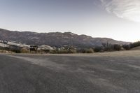 an empty road in the middle of the mountains with a stop sign in the distance