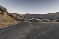 an empty road in the middle of the mountains with a stop sign in the distance