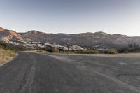 an empty road in the middle of the mountains with a stop sign in the distance