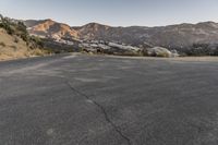 an empty road in the middle of the mountains with a stop sign in the distance