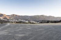 an empty road in the middle of the mountains with a stop sign in the distance