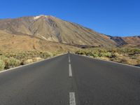 an empty road in the middle of the desert with mountains in the background or the sky