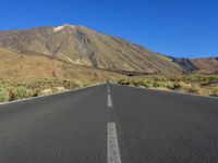 an empty road in the middle of the desert with mountains in the background or the sky