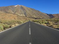 an empty road in the middle of the desert with mountains in the background or the sky