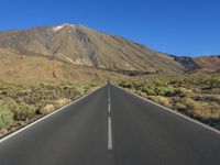 an empty road in the middle of the desert with mountains in the background or the sky