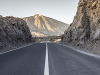 the long and straight empty road passes through a canyon and mountains in the morning sun