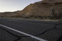 a empty road with a mountain in the distance and a car parked on the side