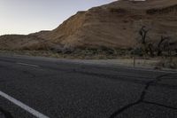 a empty road with a mountain in the distance and a car parked on the side