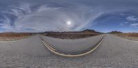 an empty street on a cloudy day with mountains behind it in the distance in a fish - eye lens