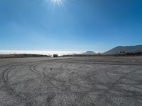 an empty road with cars driving down it and mountains in the background and blue sky above