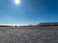 an empty road with cars driving down it and mountains in the background and blue sky above