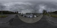 a picture of an empty street with boats parked by a fenced in area on a cloudy day