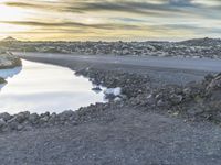 an empty road that has a body of water in it and there is a person sitting on the ground in the water