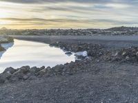 an empty road that has a body of water in it and there is a person sitting on the ground in the water