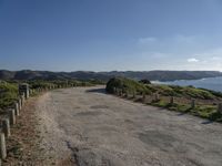 the road is wide and empty on a mountain side next to the ocean to the right