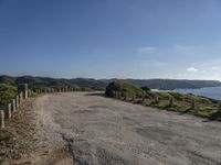 the road is wide and empty on a mountain side next to the ocean to the right