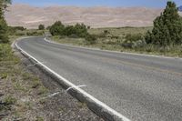 an empty empty road is shown by tall mountains in the distance with a small road marking and a single yellow line